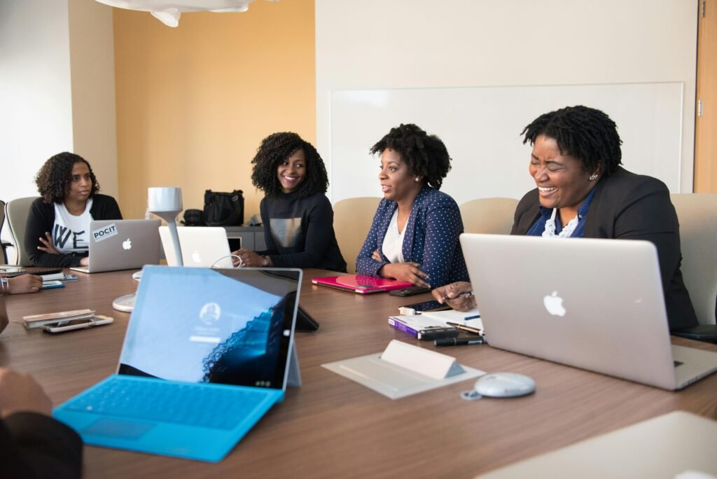 pexels-photo-1181360-1181360 Group of women engaged in a collaborative meeting at an office table with laptops.